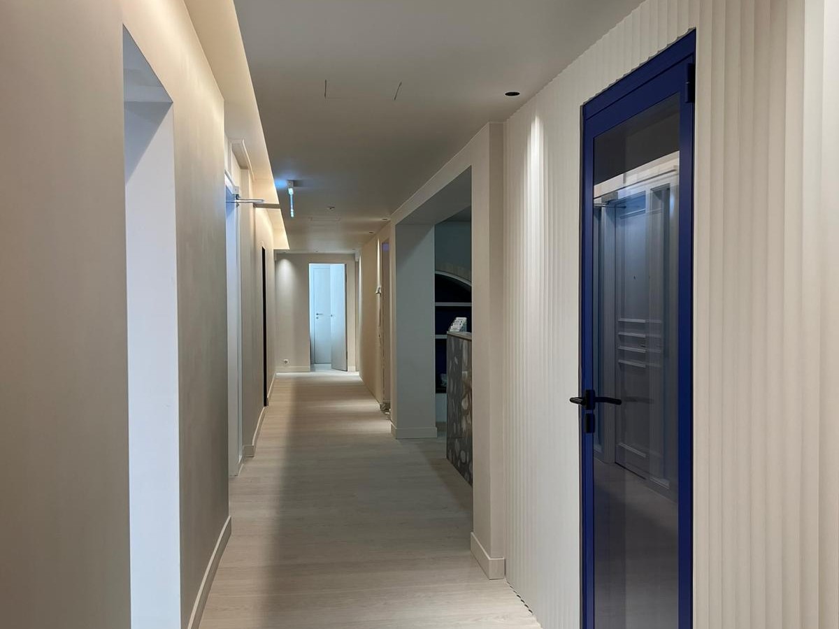 Après chantier — couloir fini, porte verrière bleue et éclairage indirect