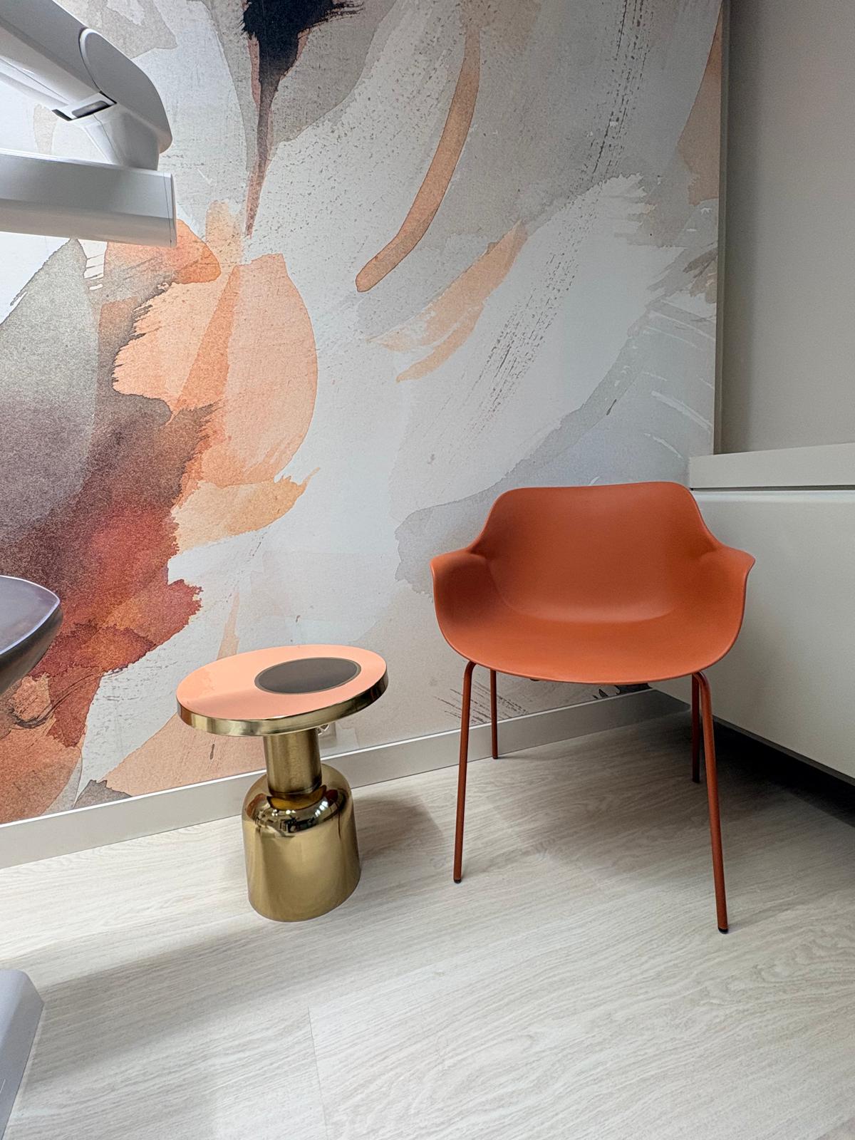 Détail salle de soin — fauteuil terracotta, guéridon laiton et papier peint aquarelle