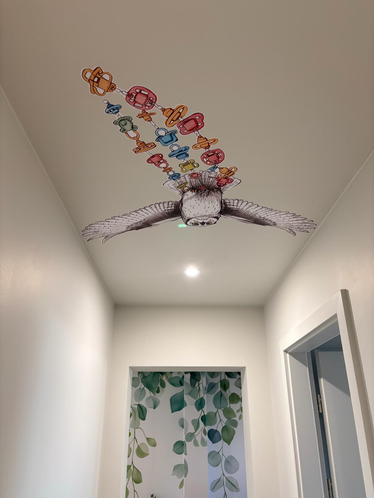 Plafond du couloir — fresque hibou en vol portant une guirlande de tétines colorées