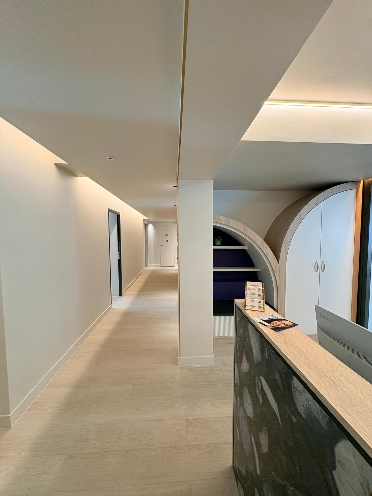 Couloir d'accueil — banque agate, niches arquées en bois et liserés laiton au plafond