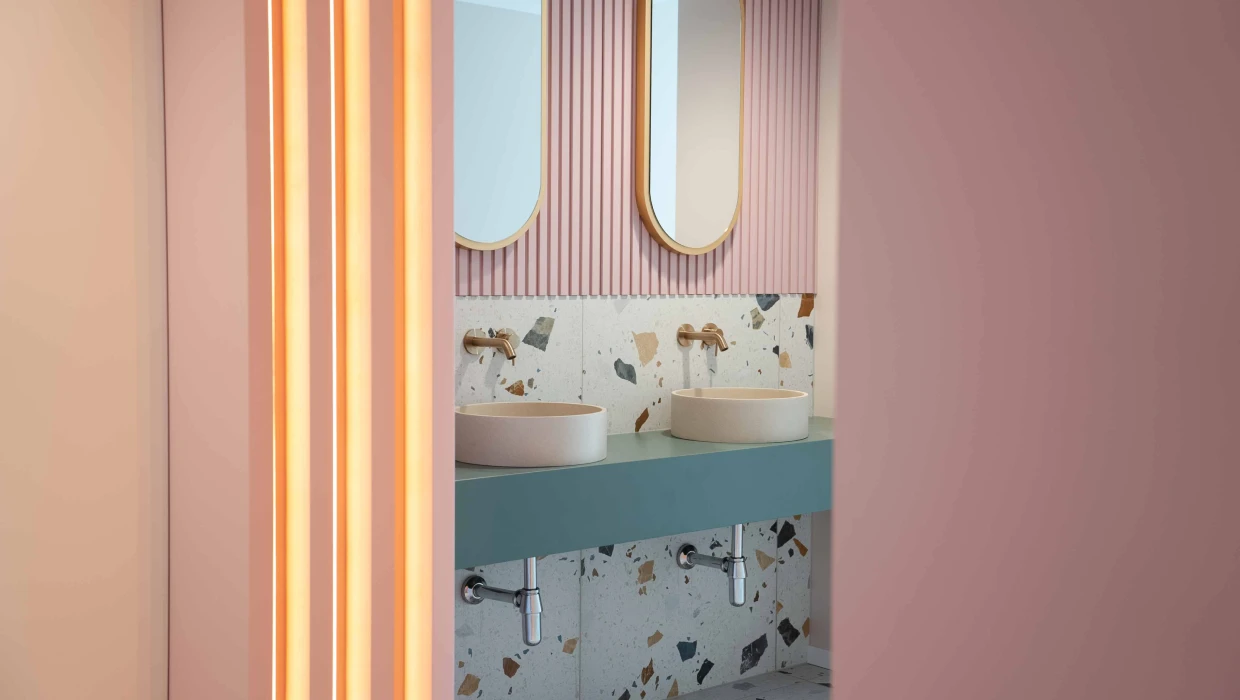 Sanitaire — miroirs roses, vasques sur plan turquoise et carrelage terrazzo