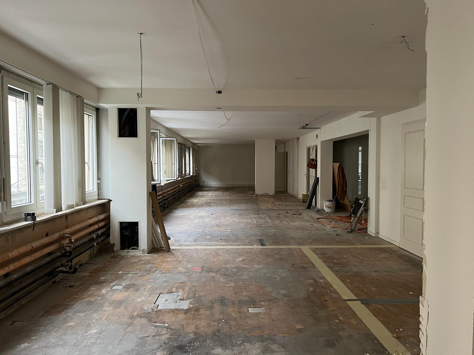 Avant chantier — vaste plateau brut, parquet à déposer et radiateurs apparents