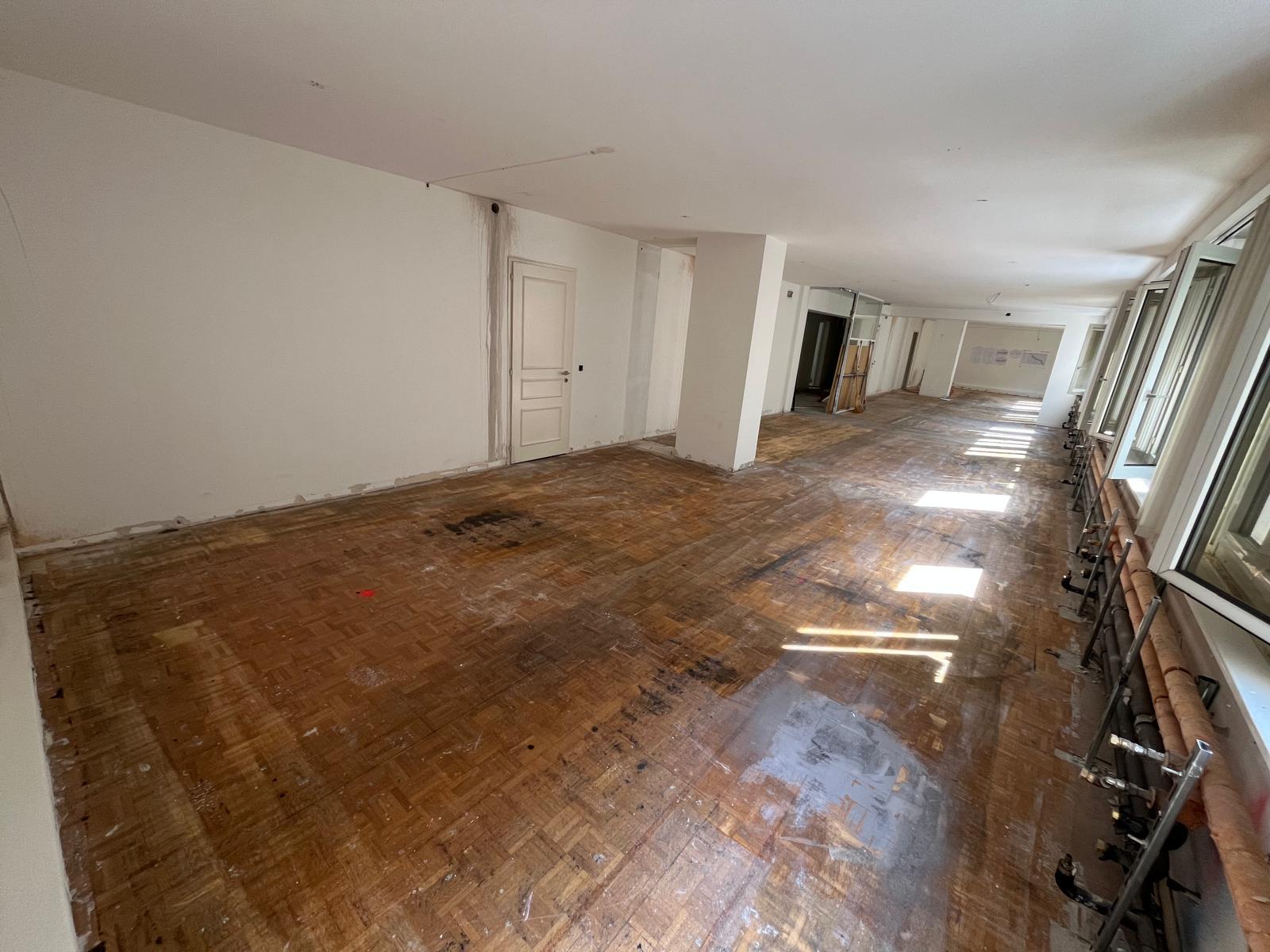 Avant chantier — plateau brut, parquet d'origine et radiateurs apparents côté fenêtres