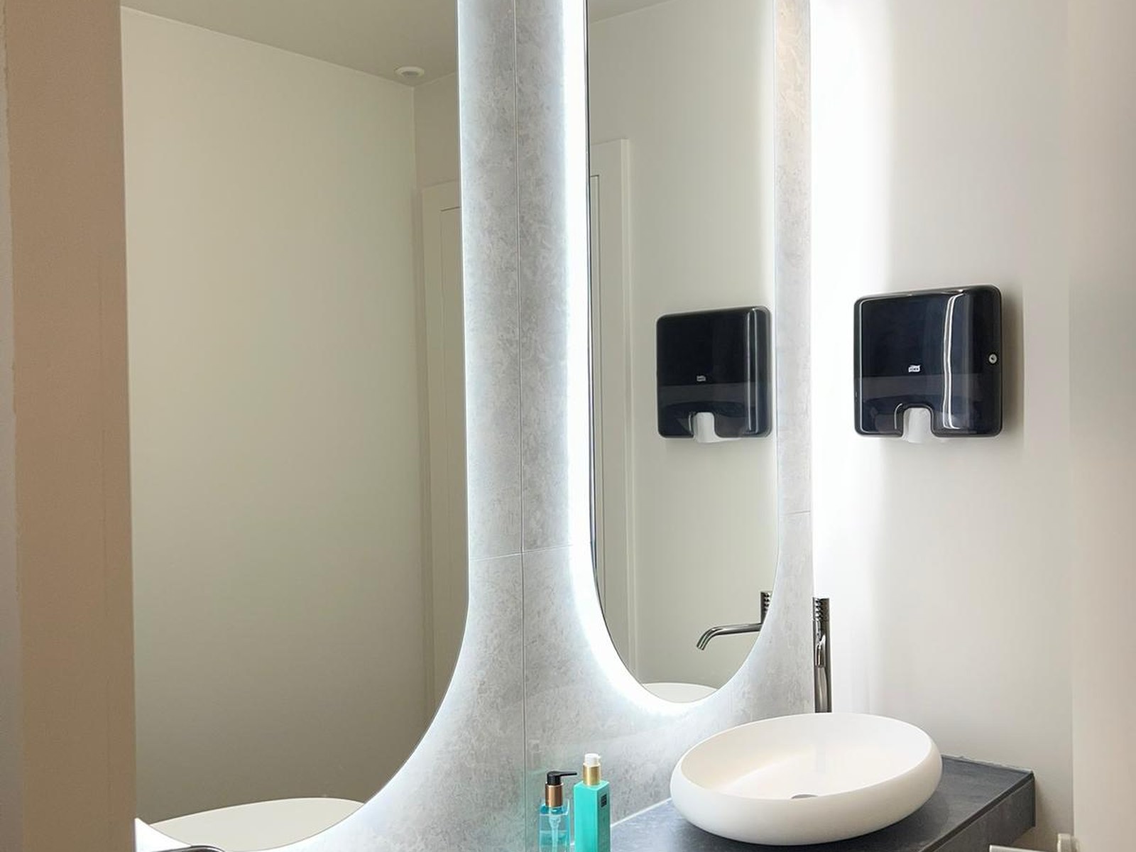 Après chantier — sanitaire rénové, vasques ovales, plan en pierre grise et miroirs rétroéclairés