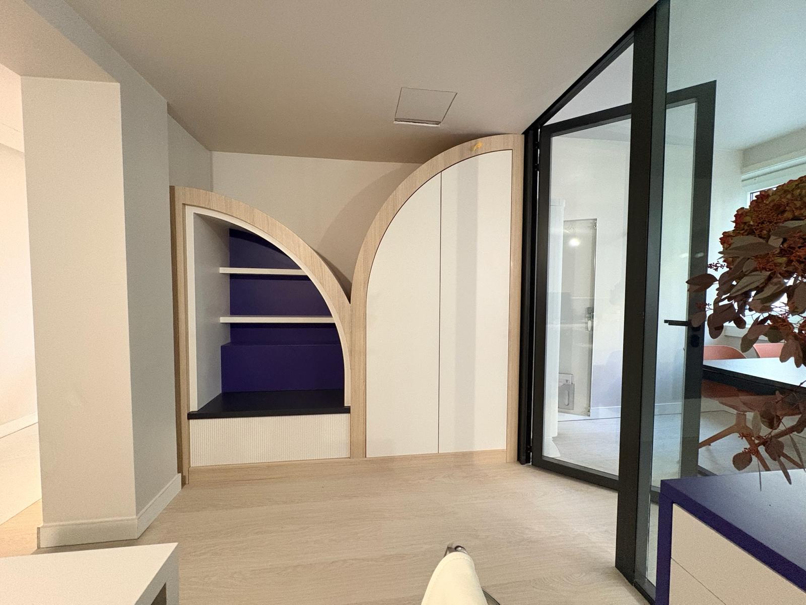 Espace accueil — niches arquées en bois clair et fond violet, verrière noire