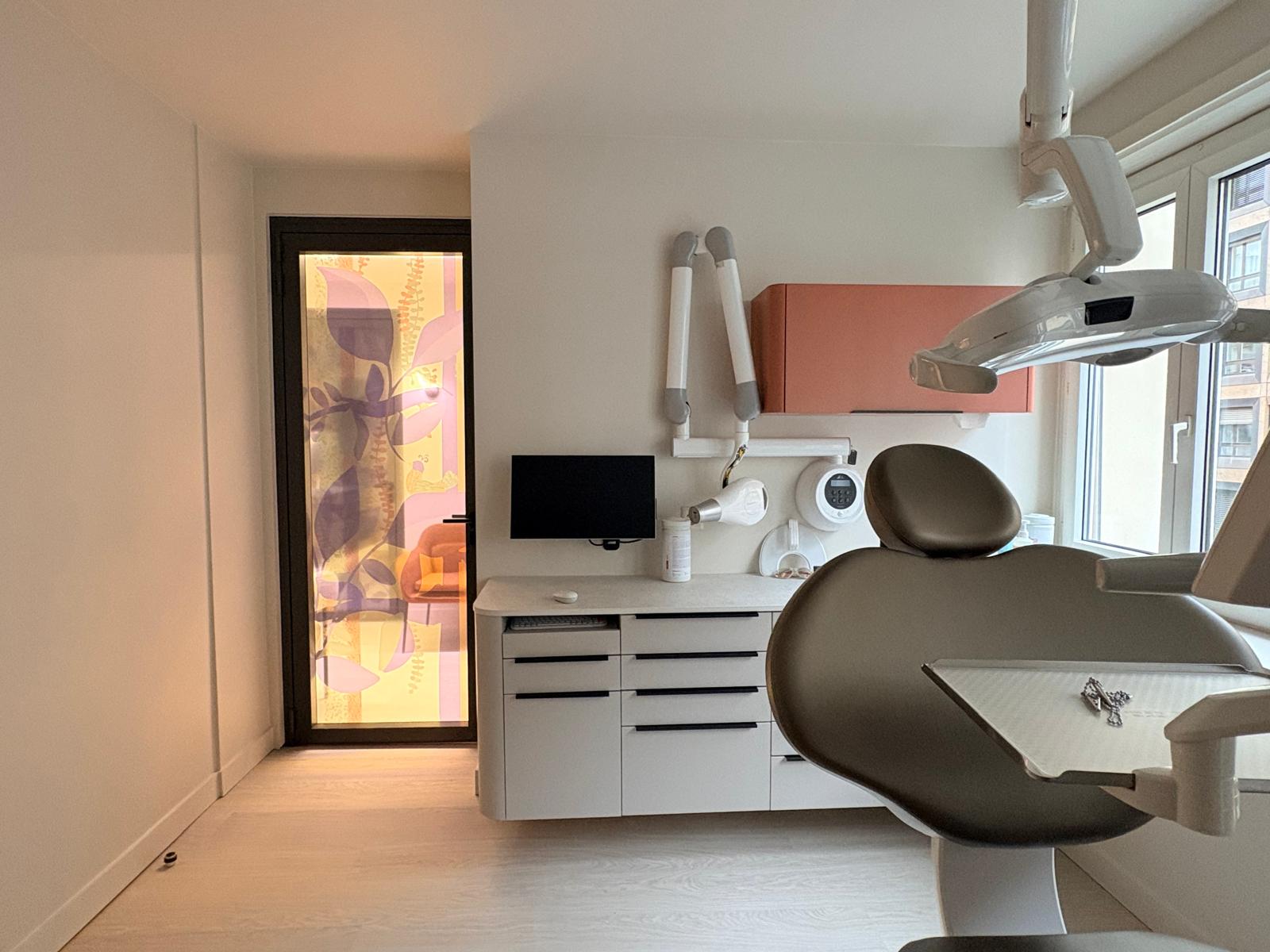 Salle de soin — meuble haut terracotta, porte vitrée à motif feuillage et fauteuil patient