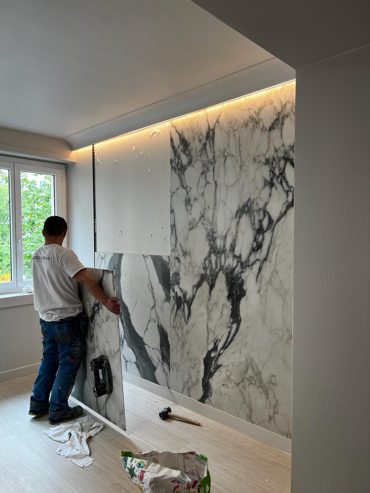 Pose en cours — habillage mural en marbre veiné Calacatta avec liseré LED