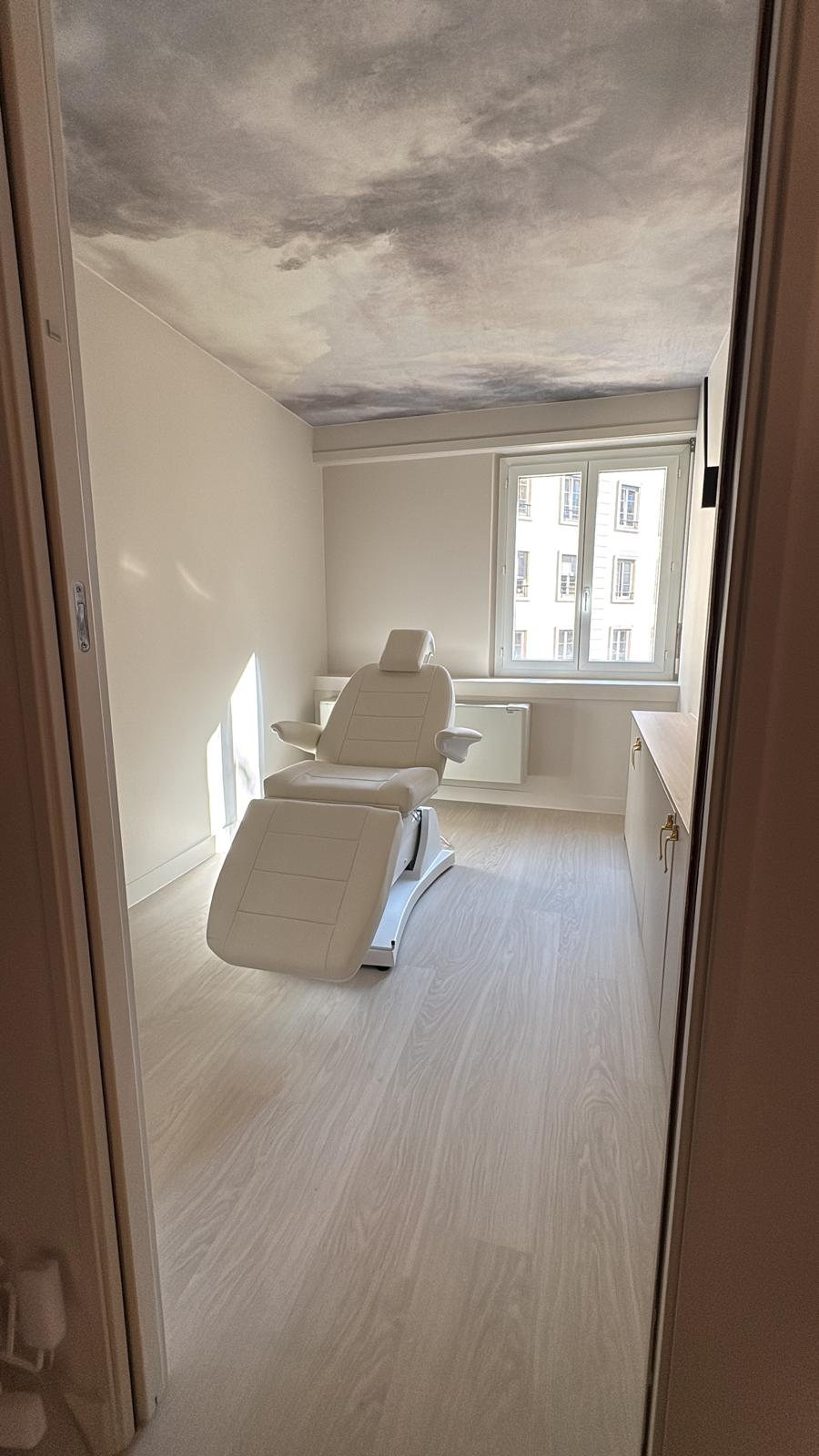 Cabine soins esthétiques — fauteuil blanc, plafond panoramique ciel nuageux et plan bois clair