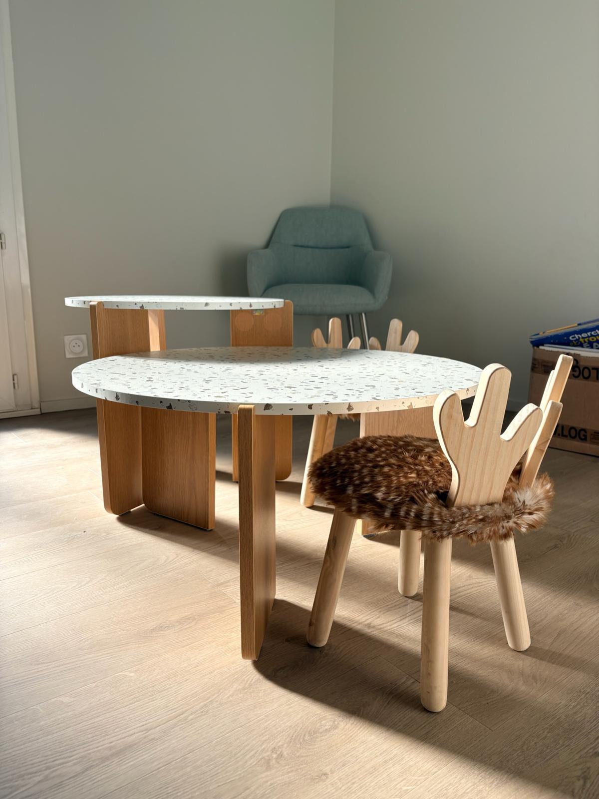 Espace enfants — table ronde terrazzo, chaises bois en forme de main et fauteuil bleu d'eau